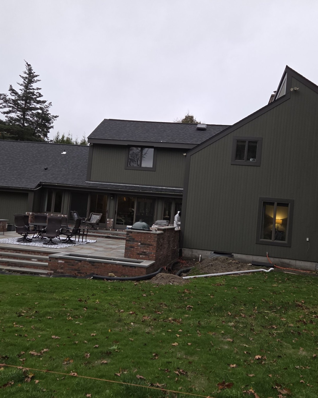Rear of the home with newly painted dark olive green siding and stone paver patio after exterior painting