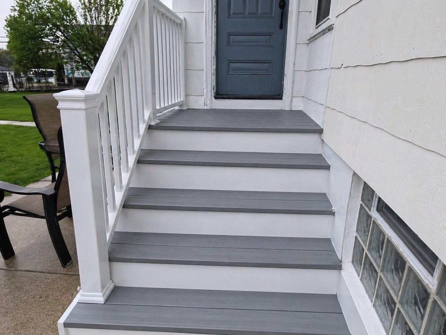 Finished porch stairs with grey treads and white risers, trim and railing after restoration
